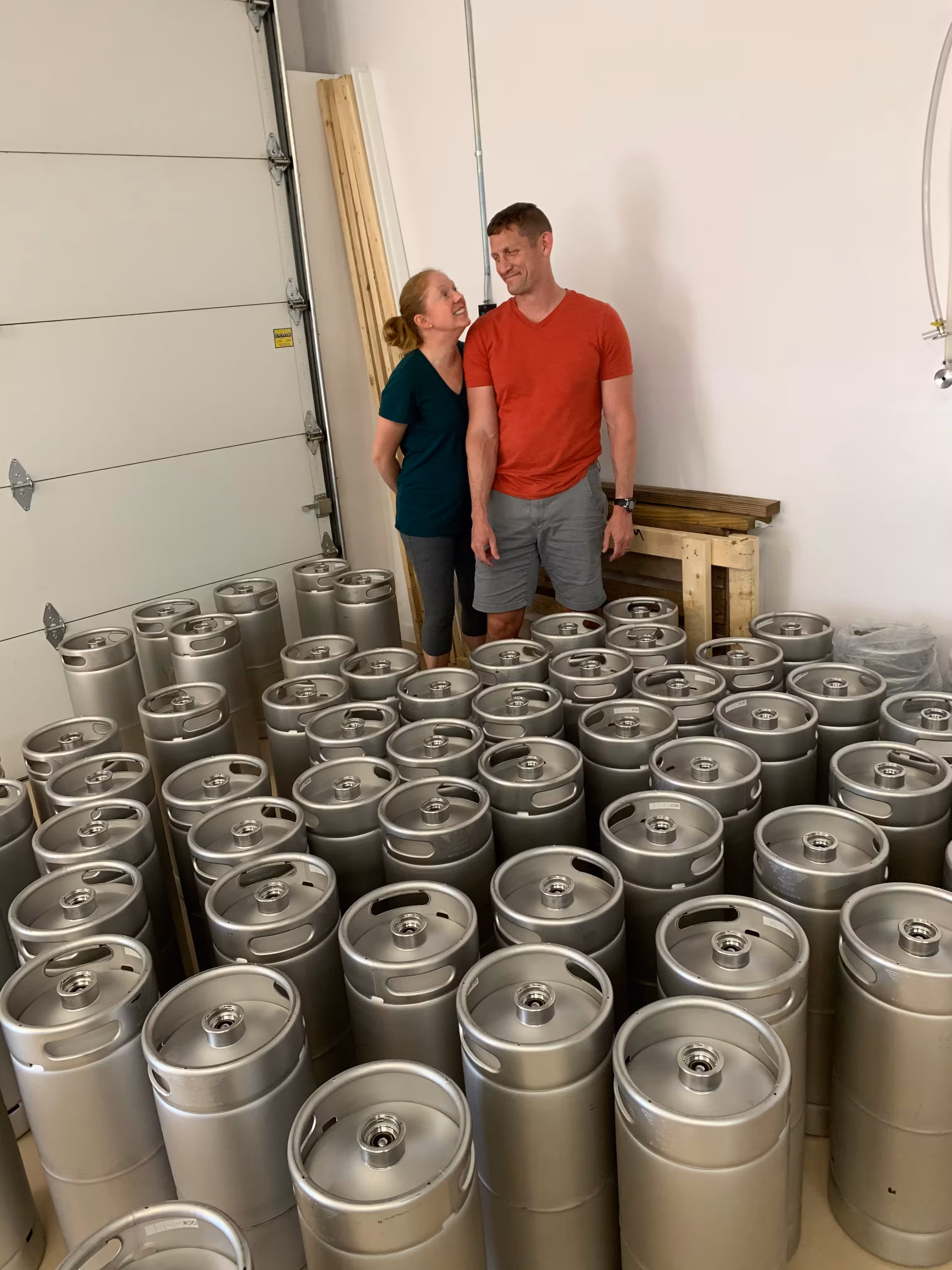Kenneth and Denise standing side by side next to their newly purchased stainless-steel kegs.