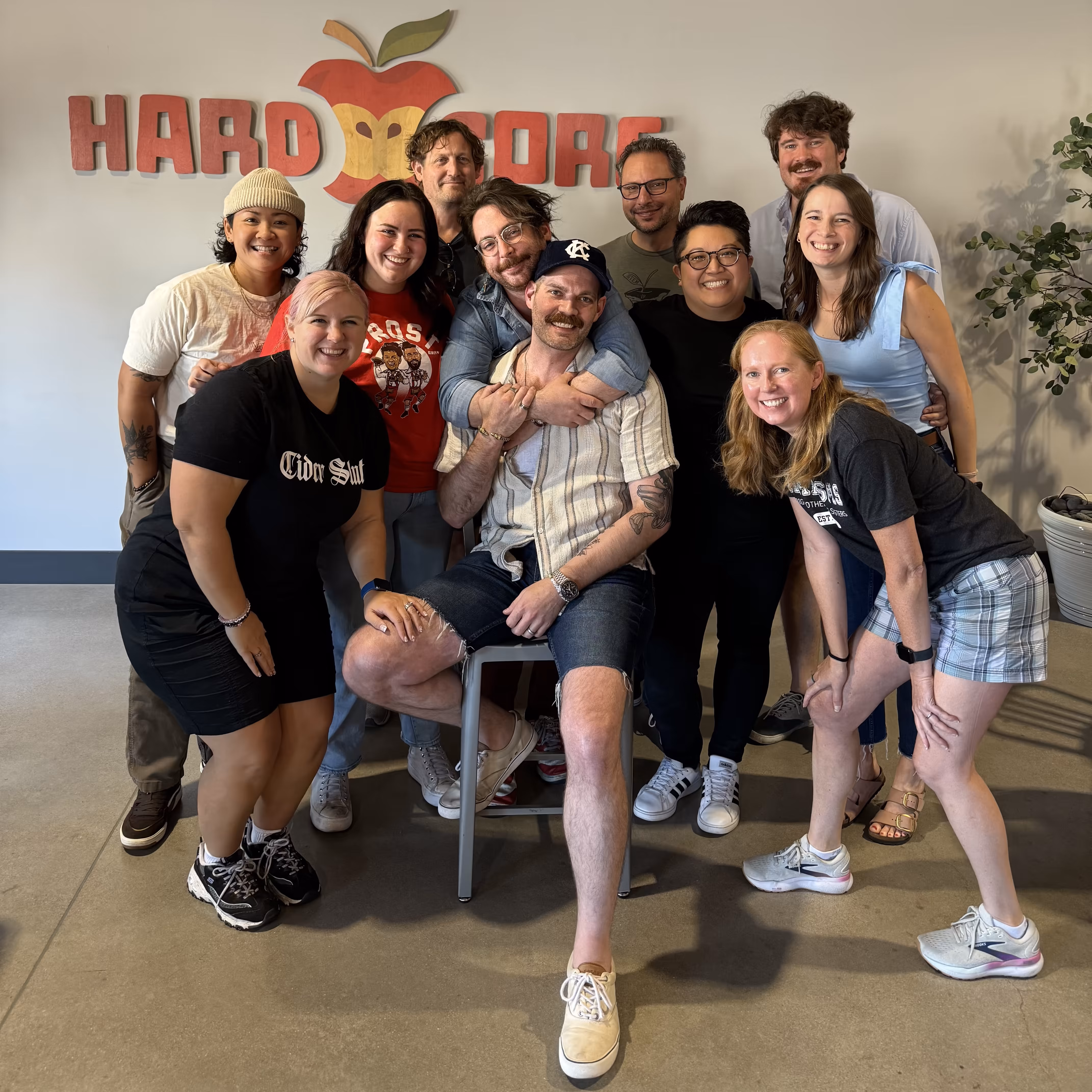 White Crow Cider team standing together in the taproom next to their hardcore sign.